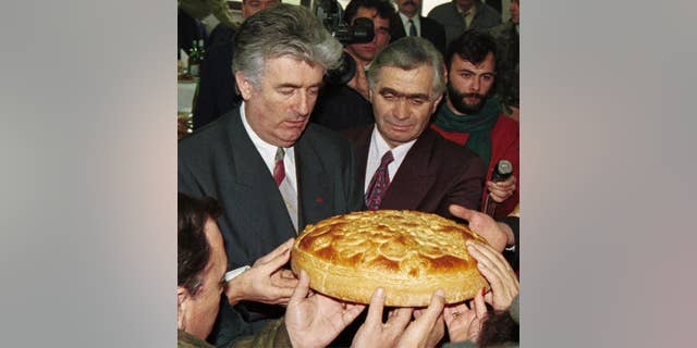 FILE - In this Jan. 9, 1996 file photo, Bonsnian Serb wartime leader Radovan Karadzic, left, and Serb member of Bosnian Presidency Momcilo Krajisnik roll the cake, marking St. Stevan, Republic of Srpska patron-saint day. Serbia's president Tomislav Nikolic has met a convicted Bosnian Serb war criminal Momcilo Krajisnik urging the protection of human rights for the Serbs living in the Balkan regions. (AP Photo/Darko Vojinovic, File)