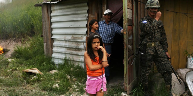 TEGUCIGALPA, HONDURAS - JULY 20: A young girl and her family stand by their home as police and the army force them and their neighbors to dismantle the shanty town after the government claimed that the settlement was illegal on July 20, 2012 in Tegucigalpa, Honduras. Land disputes are becoming increasingly frequent in Honduras which is alarming the nation's business class while sowing fears of increased political violence. In a nation where 72% of the poorest landowners hold only 11.6% of cultivated land, tensions are rising as the poor have few places to go and little opportunities for productive employment. Honduras now has the highest per capita murder rate in the world and its capital city, Tegucigalpa, is plagued by violence, poverty, homelessness and sexual assaults. With an estimated 80% of the cocaine entering the United States now being trans-shipped through Honduras, the violence on the streets is a spillover from the ramped rise in narco-trafficking. (Photo by Spencer Platt/Getty Images)