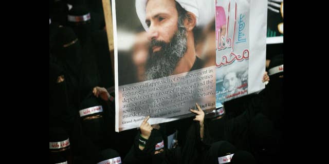 FILE - In this Sunday, Sept. 30, 2012 file photo, a Saudi anti-government protester carries a poster with the image of jailed Shiite cleric Sheik Nimr al-Nimr during the funeral of three Shiite Muslims allegedly killed by Saudi security forces in the eastern town of al-Awamiya, Saudi Arabia. Mohammed al-Nimr, the brother of Nimr al-Nimr said Wednesday, Oct. 15, 2014, on Twitter that his brother has been sentenced to death by a court in Saudi Arabia. Shiite activist Jaafar al-Shayeb in eastern Saudi Arabia says the verdict appears to have been handed down for criminal offenses over the "incitement" of Shiite protests in Saudi Arabia and neighboring Bahrain. The headbands read, "martyrdom is honor and dignity." (AP Photo, File)