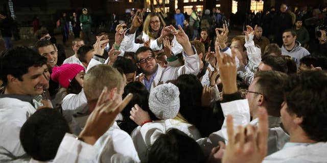 UNC Dental School students make the North Carolina State University Wolfpack sign following a candlelight vigil for their slain classmate, who, along with two others, was killed at a condominium near UNC-Chapel Hill, Wednesday, Feb. 11, 2015, in Chapel Hill, N.C. Craig Stephen Hicks appeared in court on charges of first-degree murder in the Tuesday deaths of Deah Shaddy Barakat, his wife Yusor Mohammad and her sister Razan Mohammad Abu-Salha. (AP Photo/The News & Observer, Al Drago)