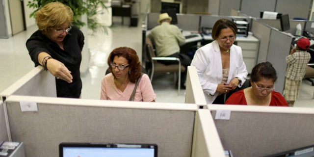 MIAMI, FL - AUGUST 01: Raisa Alvarez (L) helps Ana Celeste Reynoso as Maria Tutiven (2nd R) helps Idali Valasquez as they look for job opportunities on the computers at CareerSource Florida on August 1, 2014 in Miami, Florida. The Labor Department announced that U.S. employers added 209,000 new jobs in July and that the unemployment rate edged up to 6.2 percent as more workers joined the labor force. (Photo by Joe Raedle/Getty Images)