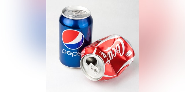 VILNIUS, LITHUANIA â OCTOBER 21, 2011: Photo of a Coca-Cola and Pepsi classic 330 ml cans. Concept of competitiveness as Coca-Cola can is lying empty and crashed while Pepsi is still full and standing.