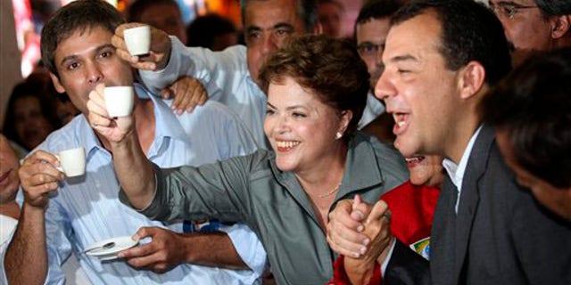 Brazil's Workers party presidential candidate Dilma Rousseff, center, holds up a cup of coffee at a coffee shop during a campaign rally in Rio de Janeiro, Brazil, Monday, Sept. 20, 2010.