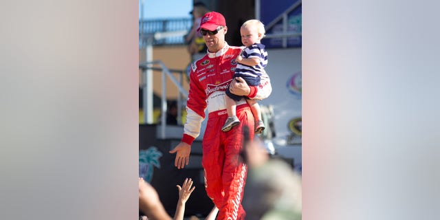 Kevin Harvick holds his with son, Keelan, as they greet fans during driver introductions before the NASCAR Sprint Cup Series auto race in Homestead, Fla., Sunday, Nov. 17, 2013. (AP Photo/J Pat Carter)