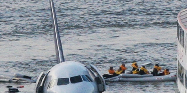 FILE - In this Jan. 15, 2009 file photo, passengers in an inflatable raft move away from US Airways Flight 1549 that went down in the Hudson River in New York. Capt. Chesley "Sully" Sullenberger III, First Officer Jeff Skiles and some passengers who were on the plane on Wednesday, Jan. 15, 2014 are expected to join some of the ferry crews who rescued them from the cold waters five years ago. (AP Photo/Bebeto Matthews, File)