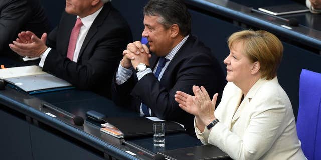German chancellor Angela Merkel sits next to minister of the economy, Sigmar Gabriel and Foreign Minister Frank-Walter Steinmeier, from right, in the German parliament Bundestag in Berlin, Germany, Thursday, July 7 2016. In her government declaration the chancellor commented on the German strategy for the upcoming NATO summit. (Wolfgang Kumm/dpa via AP)