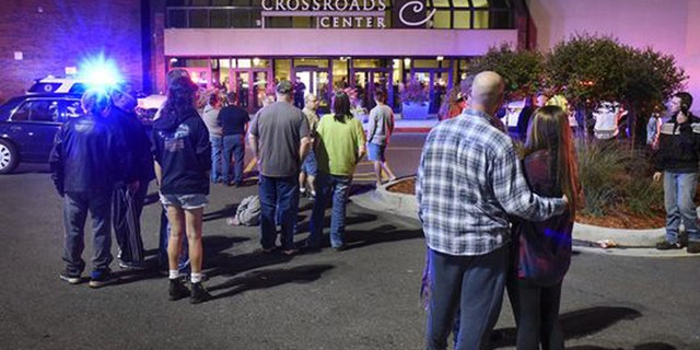 People stand near the entrance on the north side of Crossroads Center mall between Macy's and Target as officials investigate a reported multiple stabbing incident, Saturday, Sept. 17, 2016, in St. Cloud, Minn. Police said multiple people were injured at the St. Cloud shopping mall on Saturday evening in an attack possibly involving both shooting and stabbing. The suspect is believed to be dead, St. Cloud Police Sgt. Jason Burke told the St. Cloud Times. (Dave Schwarz/St. Cloud Times via AP)