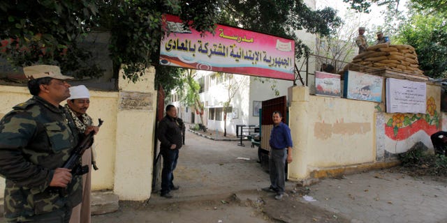 Egyptian army soldiers and plainclothes policemen guard a polling station in Cairo, Egypt, Monday, Jan. 13, 2014. The January 14-15 vote on the draft constitution will be the first real test of the post-Mohammed Morsi regime. A comfortable "yes" vote and a respectable turnout would be seen as bestowing legitimacy, while undermining the Islamists' argument that Morsi remains the nation's elected president. (AP Photo/Amr Nabil)