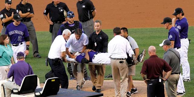 Colorado Rockies starting pitcher Juan Nicasio is surrounded by teammates and medical personnel on his way off the field after Washington Nationals' Ian Desmond hit him in the head with a line drive during the second inning of a baseball game Friday, Aug. 5, 2011 in Denver. (AP Photo/Barry Gutierrez)