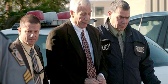 Nov. 5: In this photo provided by the Pennsylvania Office of Attorney General, former Penn State football defensive coordinator Gerald "Jerry" Sandusky, is escorted in handcuffs to a waiting police car in Bellefonte, Pa.