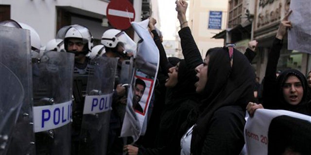 April 18, 2012: Bahraini anti-government activist Zainab al-Khawaja, second right, gestures and chants slogans in front of riot police during a protest in downtown Manama, Bahrain.
