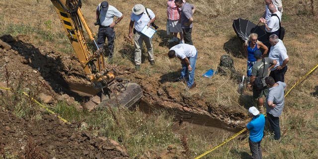 Yellow tape marks the site as an excavator digs a location that is being investigated at Pristina University campus following suspicions of a mass grave of people missing since the 1999 war, in Pristina on Wednesday, July 13, 2016. About 1,650 people remain missing since the end of the war with Serbia in 1999. (AP Photo/Visar Kryeziu)