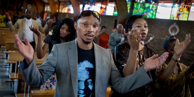 Mourners attend an early morning church service in memory of Nelson Mandela at the Regina Mundi church, which became one of the focal points of the anti-apartheid struggle, in Soweto, Johannesburg, People in South Africa are taking part in a day of "prayer and reflection" for late President Nelson Mandela. (AP Photo/Ben Curtis)