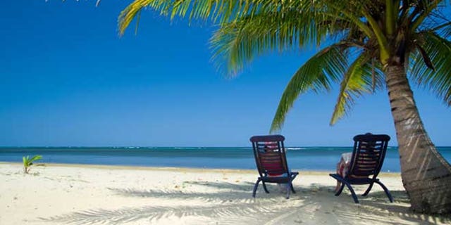 Relaxing under a palm tree on remote beach