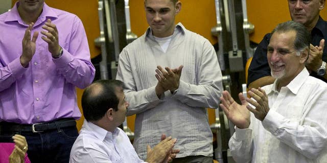 FILE - In this Dec. 20, 2014 file photo, Elian Gonzalez, center, the young Cuban rafter who was at the center of a bitter custody battle in 2000 between relatives in Miami and his father in Cuba, is recognized with applause during the legislative session at the National Assembly in Havana, Cuba. Cuban government website Cubadebate reported Friday, July 15, 2016, the now 22-year-old Gonzalez received his diploma in industrial engineering from the University of Matanzas. Flanked by Fernando Gonzalez, bottom left, and Rene Gonzalez, front right, members of the "Cuban Five" spy ring. (AP Photo/Ramon Espinosa)