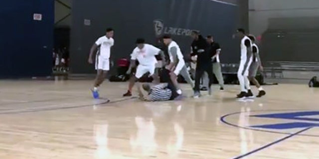 Players surrounded a fallen referee after a fight breaks out at an AAU game in Cartersville, Ga. Sunday