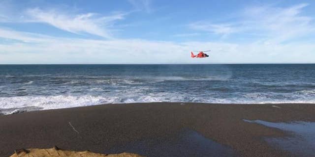 A U.S. Coast Guard helicopter searches a beach about two miles north of Cape Blanco, Oregon