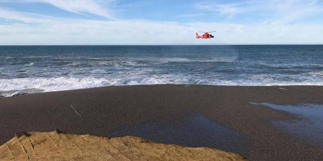 A U.S. Coast Guard helicopter searches a beach about two miles north of Cape Blanco, Oregon