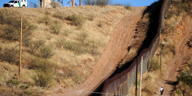 FILE 2011: A woman walks near the border fence between Mexico and the United States in Nogales.