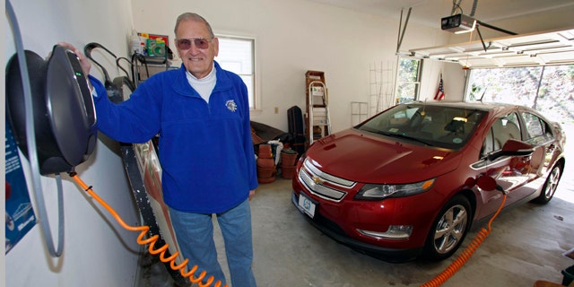 This Friday, March 25, 2011 photo shows James Brazell as he poses with a charging unit for his Chevy Volt electric car at his home in Asheville, N.C. Brazell plugs the car in after short trips. "Pretty much I top it up every time I bring it into the garage," he said.    (AP Photo/Chuck Burton)