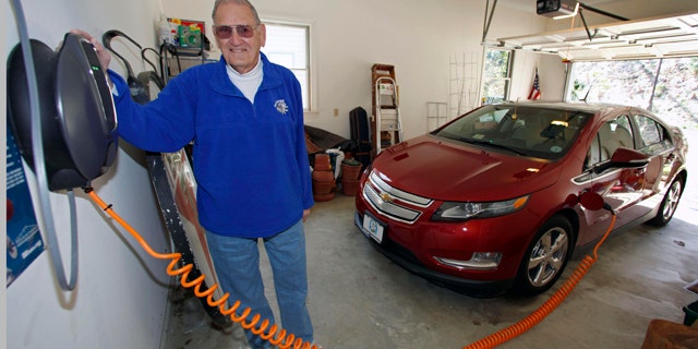 This Friday, March 25, 2011 photo shows James Brazell as he poses with a charging unit for his Chevy Volt electric car at his home in Asheville, N.C. Brazell plugs the car in after short trips. "Pretty much I top it up every time I bring it into the garage," he said. (AP Photo/Chuck Burton)