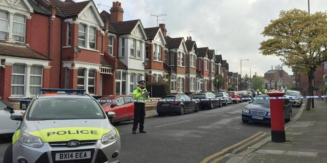 Police officers man the cordoned off area in London's Harlesden Road Friday, April 28, 2017, after British counter-terror police have shot a woman and arrested several people in raids in London and southeastern England. The injured suspect has been hospitalized in serious condition after the raid in northwest London. (Harriet Line/PA via AP)