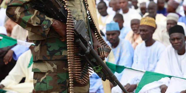 FILE - In this Thursday, Aug. 8, 2013 file photo, a Nigerian soldiers stand guard during Eid al-Fitr celebrations in Maiduguri, Nigeria. Nigeria’s military on Saturday, Feb. 14, 2015, repelled an attack on a northeastern town by Boko Haram Islamic extremists who, as they retreated, warned residents not to participate in the country’s elections in March. (AP Photo/Sunday Alamba, File)