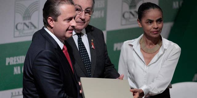 In this Aug. 6, 2014 photo, Brazilian presidential candidate Eduardo Campos, left, and his running mate Marina Silva, pose for a photo with the National Confederation of Agriculture President Joao Martins da Silva Junior, in Brasilia, Brazil. The death of Campos in a plane that smashed into a white-collar neighborhood in the port city of Santos Wednesday, Aug. 13, 2014, is reshuffling the candidates and voter preferences. Political observers say Campos’ socialist party is expected to declare Silva, one of the country’s most popular politicians, as its presidential candidate in the coming days. (AP Photo/Eraldo Peres)