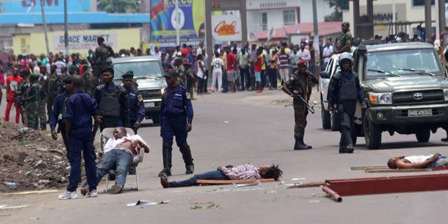 The bodies of people killed during election protests lie in the street, as Congolese troops stand near by in Kinshasa, Democratic Republic of Congo, Monday, Sept. 19, 2016. Witnesses say at least four people are dead after opposition protests against a delayed presidential election turned violent in Congo's capital. The protests were organized by activists who are opposed to longtime President Joseph Kabila, who is now expected to stay in office after his mandate ends in December. (AP Photo/John Bompengo)