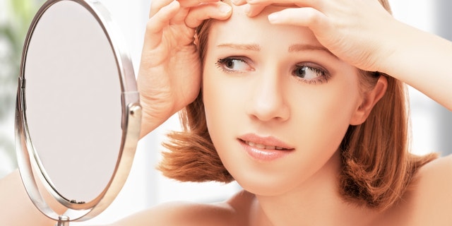 young beautiful healthy woman frightened saw in the mirror acne and wrinkles