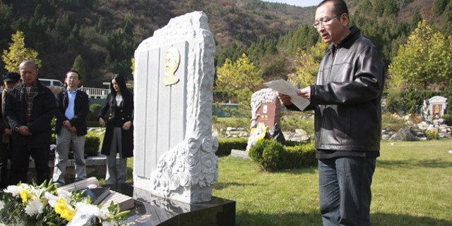 This Oct. 28, 2008 photo shows Liu Xiaobo, right, reading a letter beside the grave of Bao Zunxin, a Chinese historian and political dissident who was arrested and jailed for his role in the 1989 Tiananmen Square democracy protests in Beijing, China.