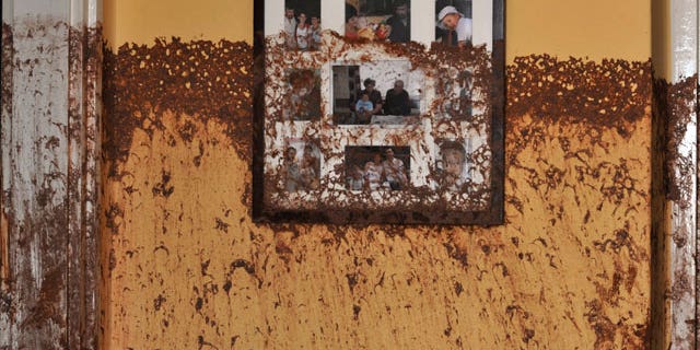 Family photos on a wall show the height of the sludge after a flood of toxic mud broke into a home in the village of Kolontar, Hungary, Thursday, Oct. 7, 2010. Monday's flooding was caused by the rupture of a red sludge reservoir at a metals works in western Hungary and has affected seven towns near the Ajkai, 100 miles (160 kilometers) southwest of Budapest. The flood of toxic mud killed a yet unknown number of people, injured more than one hundred, with some people still missing.