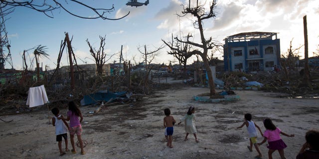 FILE--In this Thursday, Nov. 14, 2013 file photo, children run towards a U.S. military aircraft as it arrives to distribute aid to Typhoon Haiyan survivors in the destroyed town of Guiuan, Philippines on Thursday, Nov. 14, 2013. Though aid has started to arrive in Guiuan, in the nearby town of Marabut residents complained that aid has been far too slow to come (AP Photo/David Guttenfelder, File)