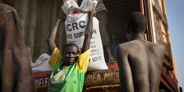 FILE - In this Thursday, Jan. 2, 2014 file photo, a man unloads food assistance supplied by the International Red Cross which arrived in the morning by truck to help the thousands who fled the recent fighting between government and rebel forces in Bor by boat across the White Nile, in the town of Awerial, South Sudan. U.N. Secretary-General Ban Ki-moon on Wednesday, Jan. 15, 2014 strongly condemned the commandeering of humanitarian vehicles and the theft of food and other desperately needed aid by government and anti-government forces in violence-torn South Sudan. (AP Photo/Ben Curtis, File)