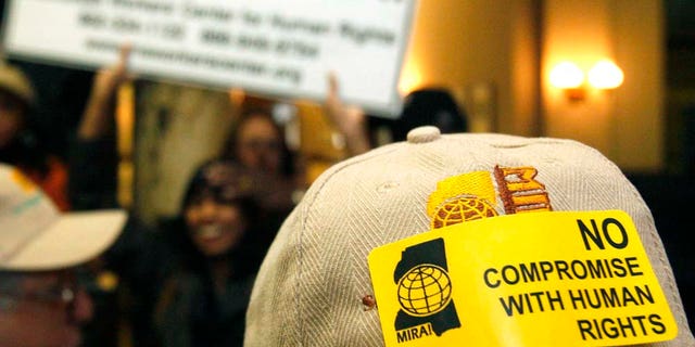 A hat sticker and sign carried by members of the Mississippi Immigrants Rights Alliance at a news conference and rally at the Capitol in Jackson, Miss., Wednesday, Jan. 12, 2011 tells of their opposition to a bill that would allow law officers to check for immigration status if they stop people for traffic offenses or other reasons. (AP Photo/Rogelio V. Solis)