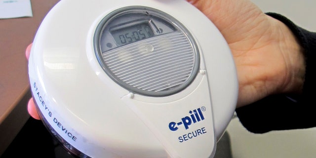 University of Vermont Psychologist Stacey Sigmon holds a tamper-proof electronic pill dispenser in her office in Burlington, Vt., Wednesday, Dec. 21, 2016. People hooked on prescription painkillers were able to use the device to take a drug at home to curb cravings and prevent abuse while waiting to get in a treatment program. Use of the device showed dramatic results in helping people who use the system remain free of illicit opioids. (AP Photo/Wilson Ring)