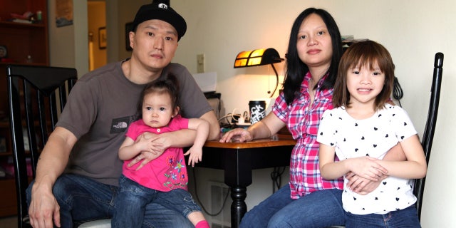 In this March 19, 2015, file photo, Korean adoptee Adam Crapser, left, poses with daughters, Christal and Christina and his wife, Anh Nguyen, in the family's living room in Vancouver, Wash.