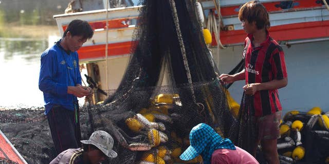 FILE - In this Sept. 3, 2013 file photo, migrant workers from Myanmar clean fishing nets aboard a trawler after a fishing trip in the Gulf of Thailand in Samut Sakhon Province, west of Bangkok, Thailand. The European Union says Thailand must take “swift and determined action” by next month to improve its fisheries and labor practices or the threat of a seafood ban will come closer.(AP Photo/Sakchai Lalit, File)