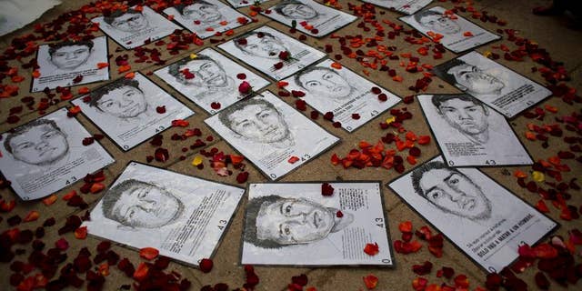 FILE - This Thursday, March 26, 2015 file photo shows drawings of some of 43 missing rural college students are surrounded by flower petals, forming the shape of a heart, during a protest marking the six-month anniversary of their disappearance, in Mexico City. Angry citizens and parents of the 43 missing students urged the country not to abandon them. (AP Photo/Rebecca Blackwell, File)