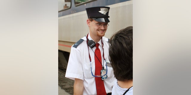 In this Aug. 21, 2007 photo, Amtrak assistant conductor, Brandon Bostian stands by as passengers board a train. He was cleared of all charged Friday in connection with a 2015 derailment that killed eight people and injured hundreds in Philadelphia. 