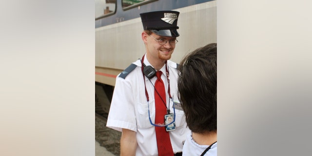 In this Aug. 21, 2007 photo, Amtrak assistant conductor, Brandon Bostian stands by as passengers board a train. He was cleared of all charged Friday in connection with a 2015 derailment that killed eight people and injured hundreds in Philadelphia.