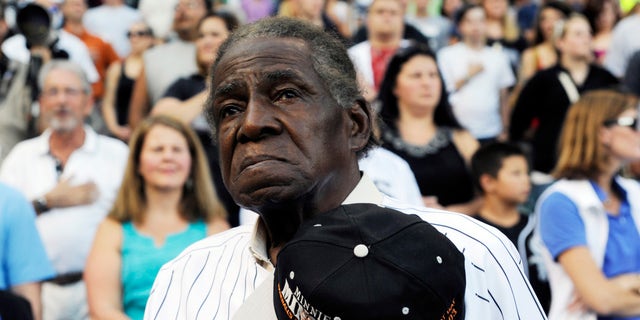 FILE - In a Aug. 24, 2013 file photo, former Negro Leaguer and Chicago White Sox player Minnie Minoso stands during the national anthem before a baseball game between the Chicago White Sox and the Texas Rangers, in Chicago.  Major league baseball's first black player in Chicago, Minnie Minoso, has died. The Cook County medical examiner confirmed his death Sunday, March 1, 2015. There is some question about his age but the White Sox say he was 92. (AP Photo/David Banks, File)