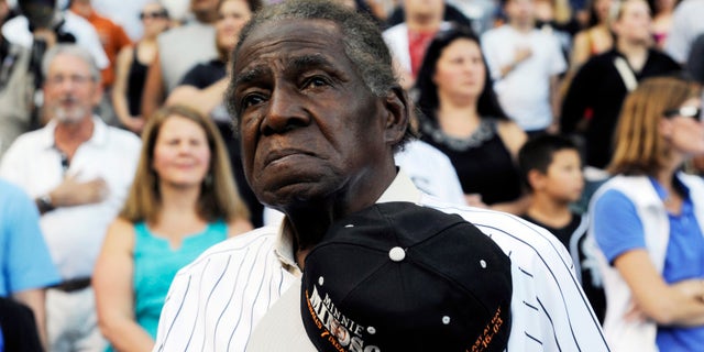 FILE - In a Aug. 24, 2013 file photo, former Negro Leaguer and Chicago White Sox player Minnie Minoso stands during the national anthem before a baseball game between the Chicago White Sox and the Texas Rangers, in Chicago. Major league baseball's first black player in Chicago, Minnie Minoso, has died. The Cook County medical examiner confirmed his death Sunday, March 1, 2015. There is some question about his age but the White Sox say he was 92. (AP Photo/David Banks, File)