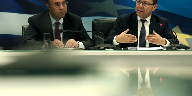 Greek Finance Minister Yiannis Stournaras, right, speaks next to Deputy Finance Minister Christos Staikouras during a press conference about Greece's EU presidency in Athens, on Tuesday, Jan. 7, 2014. Greek authorities have imposed an 18-hour ban on protests across the center of Athens during events planned Wednesday to mark the inauguration of the nation's six-month presidency of the European Union.(AP Photo/Petros Giannakouris)