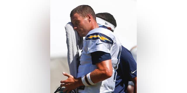 San Diego Chargers quarterback Philip Rivers wipes away the sweat from unseasonably warm weather during practice at a NFL football training camp Monday, Aug. 4, 2014, in San Diego. (AP Photo/Lenny Ignelzi)