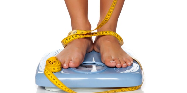 woman's feet on a domestic weight scale and measuring tape around them