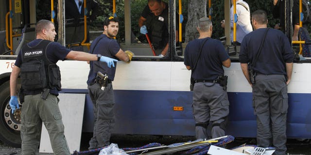Israeli policemen inspect a bus after an explosive device detonated in a Tel Aviv suburb, Sunday, Dec. 22, 2013. A small bomb exploded on board the bus just moments after it had been evacuated on Sunday, police said, adding that an initial investigation suggests that Palestinian militants were behind the attack. (AP Photo/Tomer Appelboum) ISRAEL OUT
