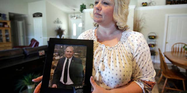 FILE - In this July 13, 2016 file photo, Laurie Holt holds a photograph of her son Josh Holt at her home, in Riverton, Utah. U.S. government officials and Holt, the mother of a Utah man jailed in Venezuela are worried about his deteriorating health. Josh Holt has been jailed since June 30 on suspicion of weapons charges. He traveled to Venezuela to marry a fellow Mormon he met online. His mother says he's innocent. (AP Photo/Rick Bowmer, File)