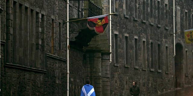 A man draped in a Saltire walks up the Royal Mile in Edinburgh, Scotland, Friday, Sept. 19, 2014. Scottish voters have rejected independence and decided that Scotland will remain part of the United Kingdom. The result announced early Friday was the one favored by Britain's political leaders, who had campaigned hard in recent weeks to convince Scottish voters to stay. It dashed many Scots' hopes of breaking free and building their own nation. (AP Photo/Scott Heppell)