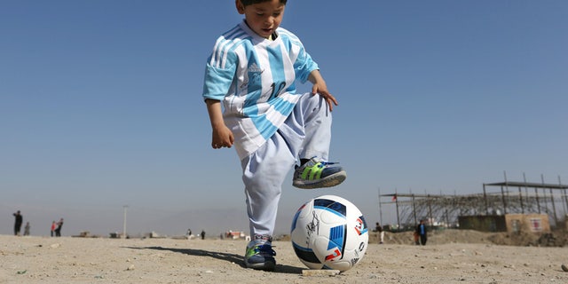 Feb. 26, 2016: Murtaza Ahmadi, a five-year-old Afghan Lionel Messi fan plays with a soccer ball during a photo opportunity as he wears a shirt signed by Messi, in Kabul, Afghanistan.